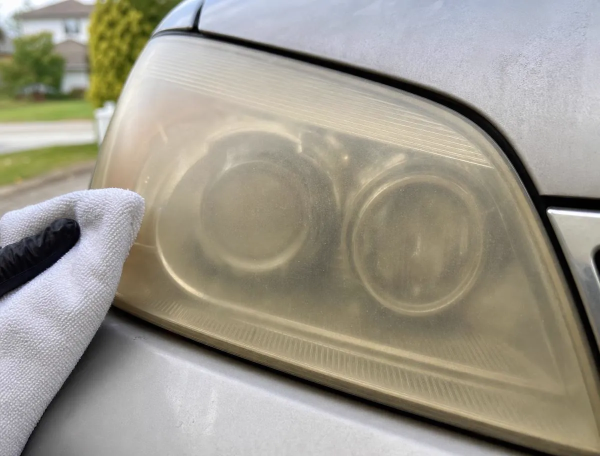 Technician prepping a yellowed headlight lens in a driveway